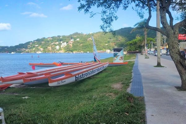 Trecho de caminhada com gramado e vista para a Lagoa da Conceição na Avenida das Rendeiras.